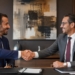 رجلان يتصافحان لتأكيد إتمام صفقة عمل داخل غرفة اجتماعات حديثة بأجواء مهنية ودافئة